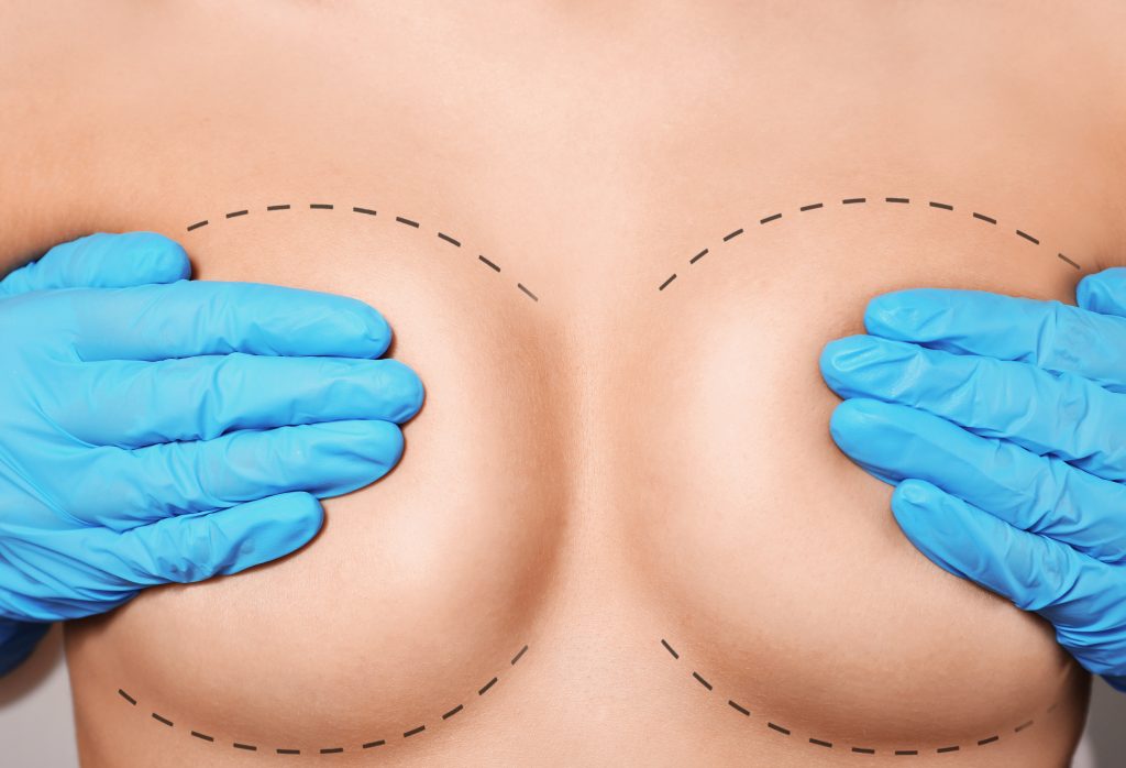 Female breasts covered with hands in rubber gloves, closeup