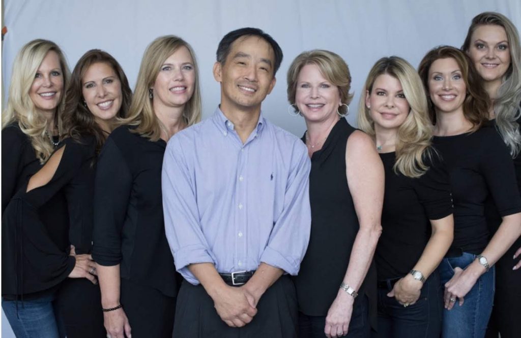 dr. chang is surrounded by the seven young ladies who work in his office