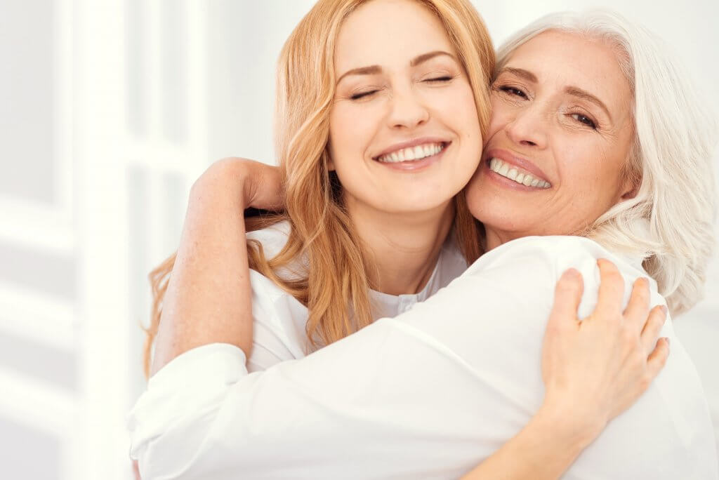 Radiant mother and daughter beaming into camera