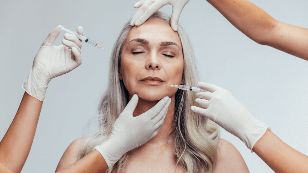 Middle-aged woman calmly receiving BOTOX injections from two skilled professionals. The practitioners, wearing medical gloves, are carefully administering the treatment into her nasolabial folds, targeting fine lines and wrinkles. The environment appears clean and professional.